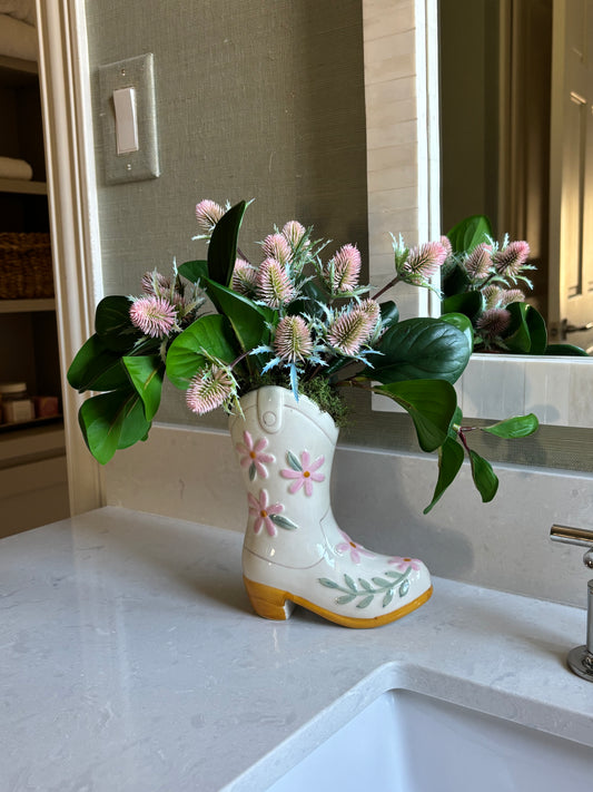 Ceramic boot shaped vase sitting on bathroom counter by sink